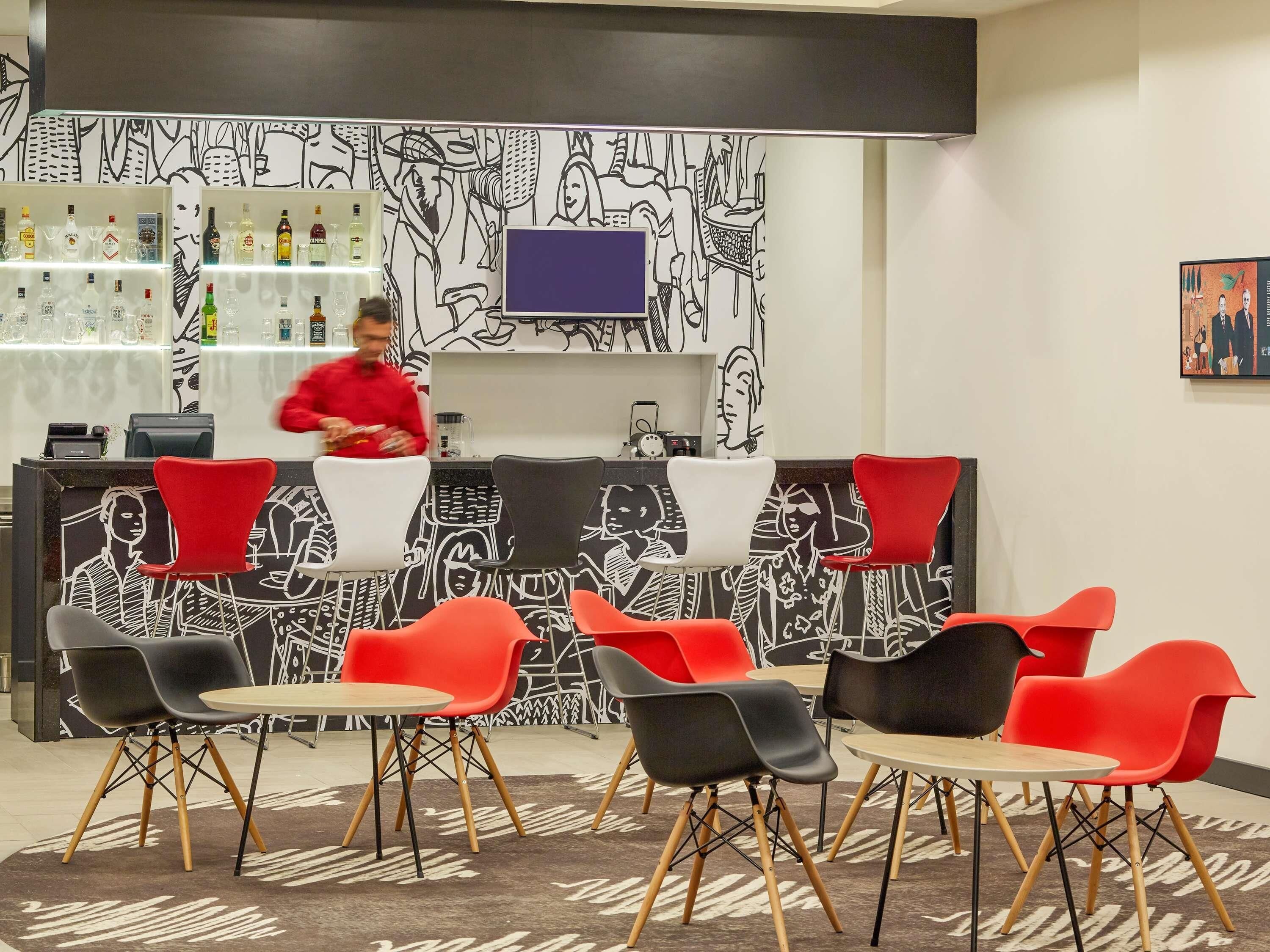A bar area with a counter, bar stools, and a wall with black and white illustrations.