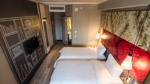 Een hotelkamer met twee bedden, een grote spiegel en een rode accentmuur.