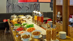 Un buffet proposant une variété de plats et de boissons, une machine à café et un buffet en bois contenant de l’ustensile de cuisine.
