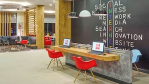 Un espace de travail moderne doté d’un tableau noir où sont écrits divers termes liés à la technologie, d’un comptoir d’accueil avec deux ordinateurs portables et de chaises rouges.