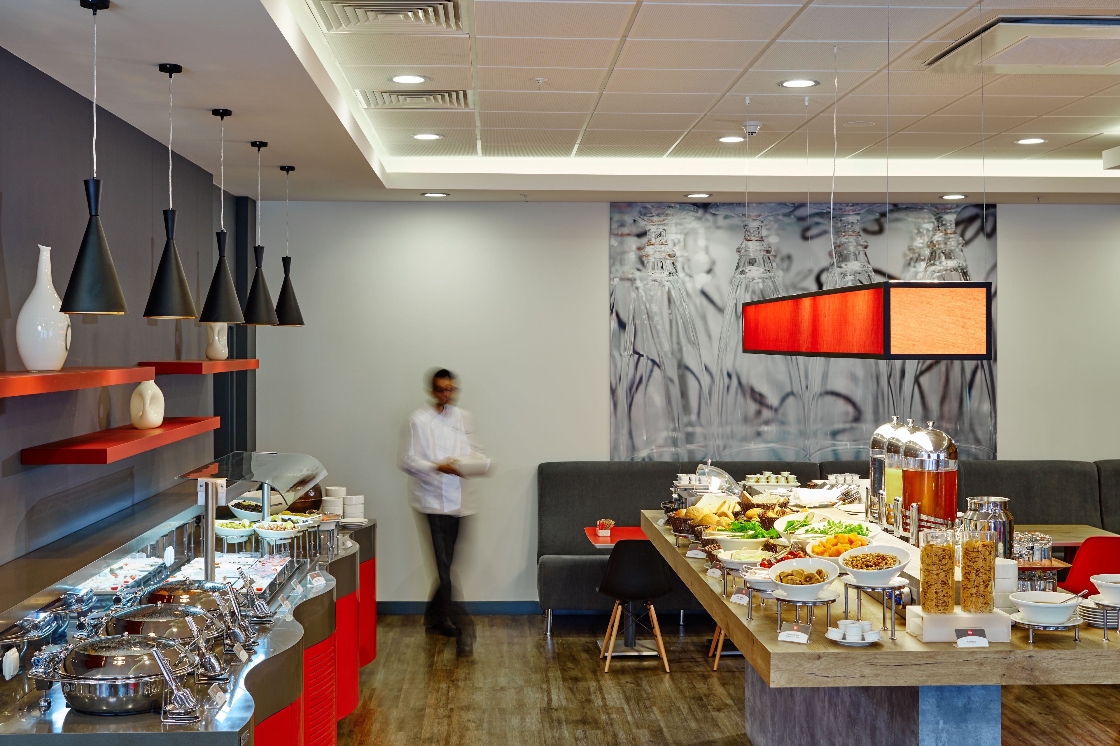 A buffet setup with various food items and a person walking in the background.