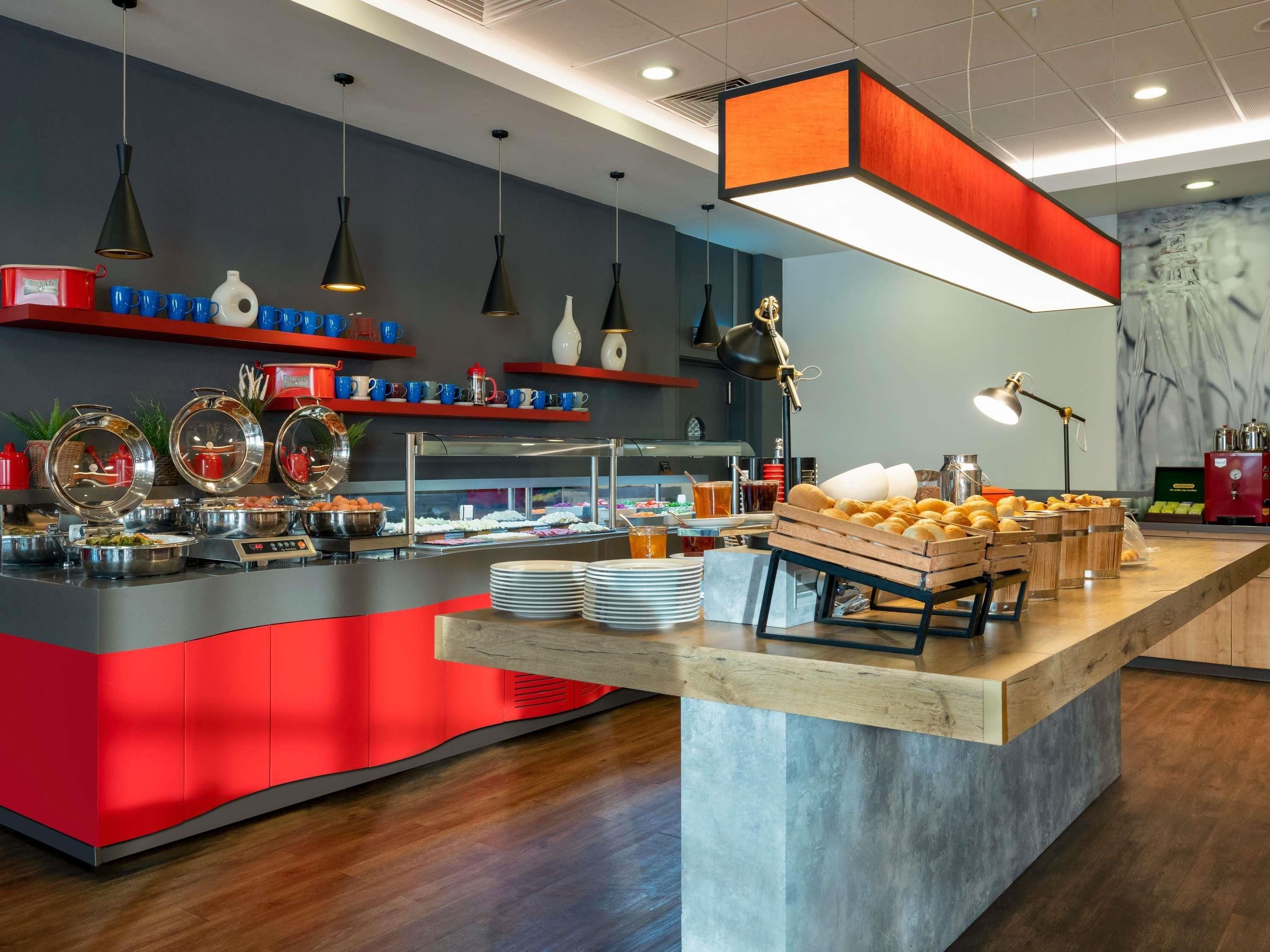 A modern breakfast bar with a red and grey color scheme, equipped with various breakfast items and a coffee station.