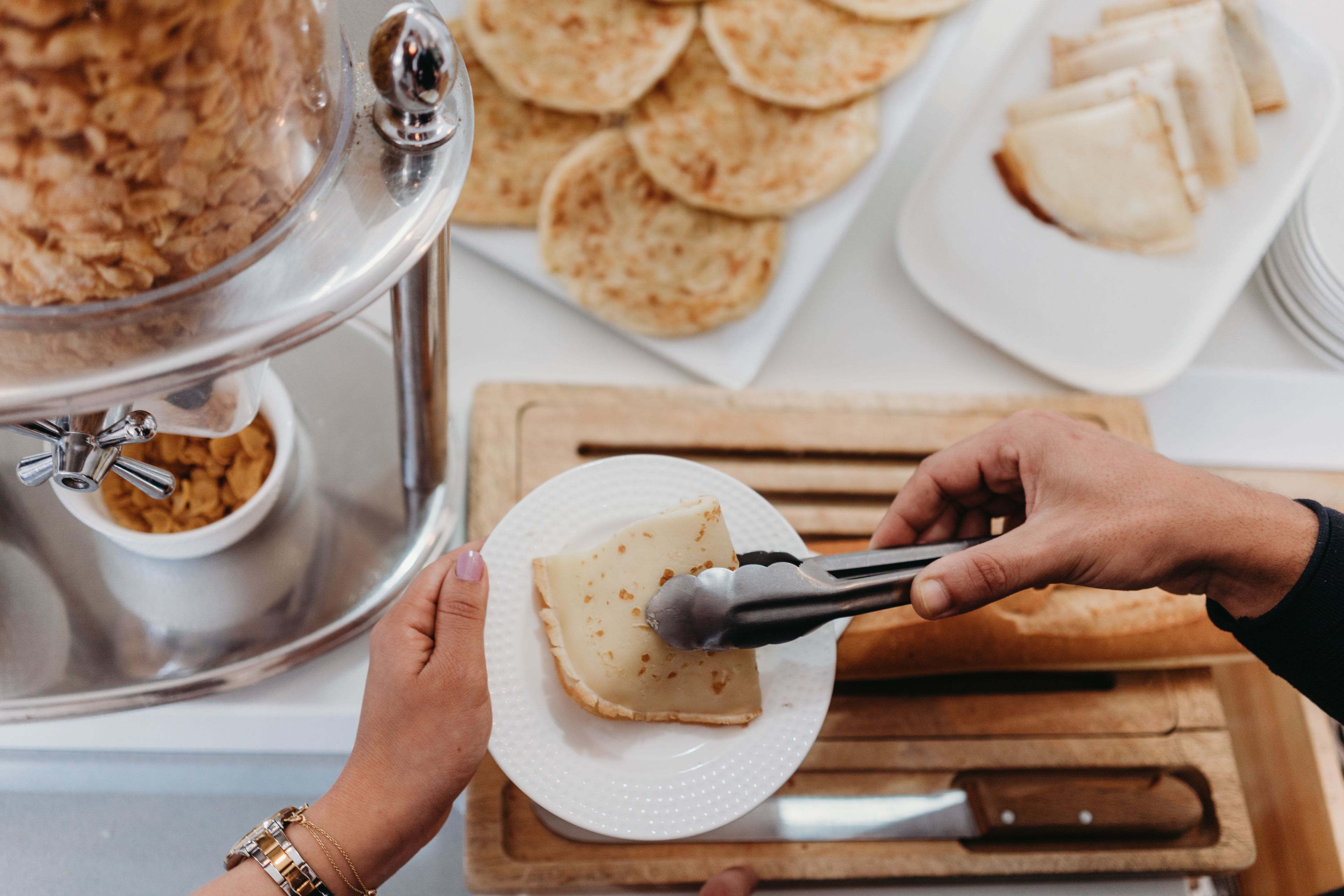Un buffet proposant une variété de plats, notamment un bol de céréales, des galettes et une assiette avec une tranche de fromage.