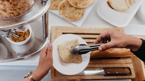 Montaje de bufé con diversos alimentos, incluyendo un tazón de cereales, panes planos y un plato con una rebanada de queso.