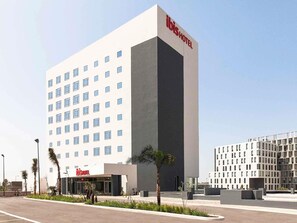Een modern hotel met een opvallend verticaal deel en een platte gevel met gelijkmatig verdeelde ramen.