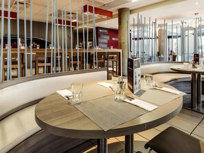 Ein Restaurantinneres mit runden Tischen, hohen Barhocker und modernem Design.
