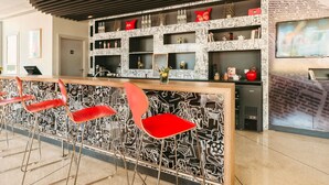 Eine Bar mit roten Stühlen, einer Theke und Regalen voller Gegenstände.