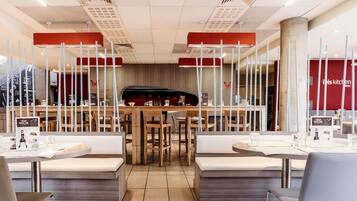 Un intérieur de restaurant moderne avec des tables et des bancs en bois, un bar central et un présentoir pour afficher le menu.