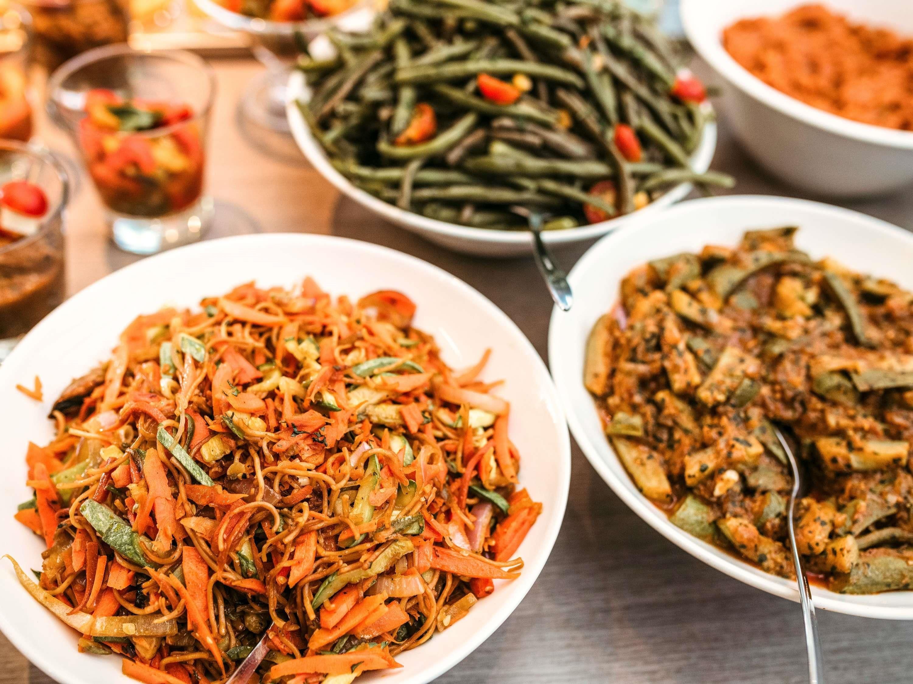 Une table garnie de différents plats, notamment des légumes sautés et un plat contenant des morceaux de viande.