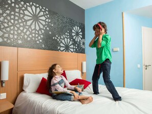 Ein Zimmer mit einem Bett, einer Wand mit geometrischem Muster und einer Tür.