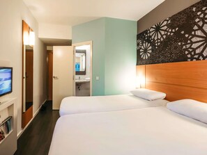 Een hotelkamer met een bed, een televisie, een badkamer en een decoratieve wand.