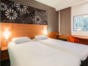 Une chambre d’hôtel avec deux lits, un bureau et une chaise.