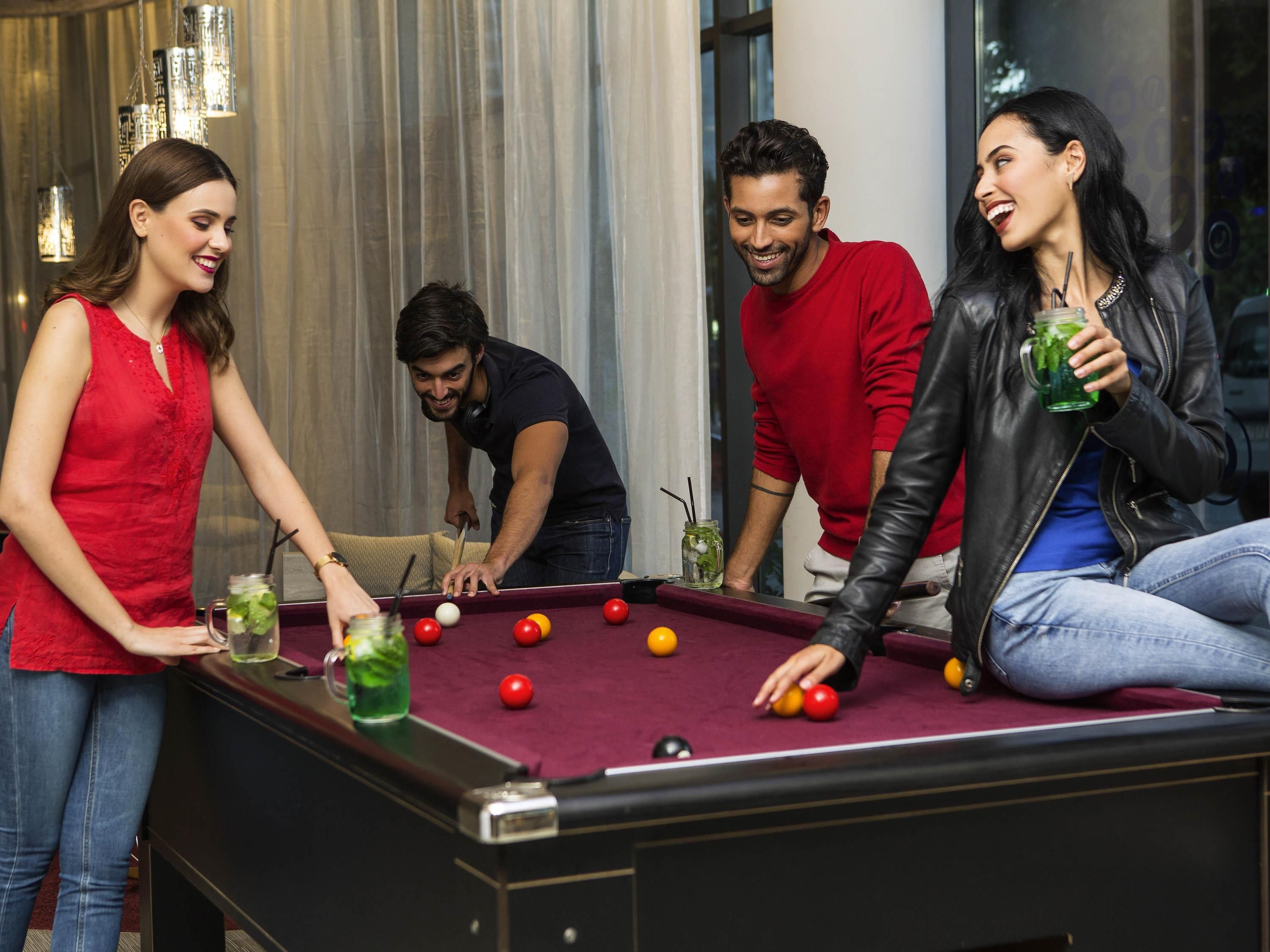 A pool table with balls, a person playing, and a drink on the table.