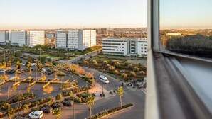 Eine Luftaufnahme eines modernen Stadtgebiets mit mehreren Hochhäusern, einem Parkplatz mit Autos und Motorrädern sowie einem klaren Himmel.