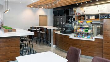 A modern bar area with a wooden counter, bar stools, and a menu display.