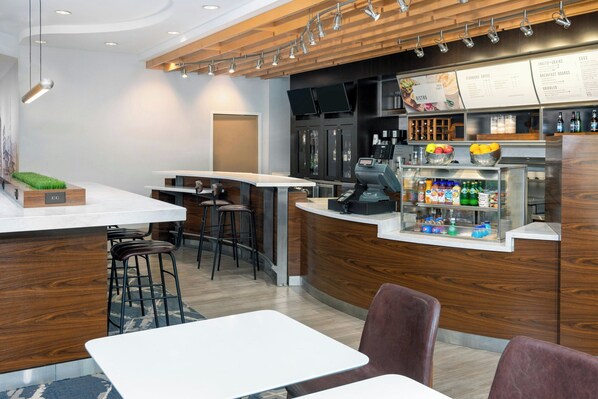 A modern bar area with a wooden counter, bar stools, and a menu display.