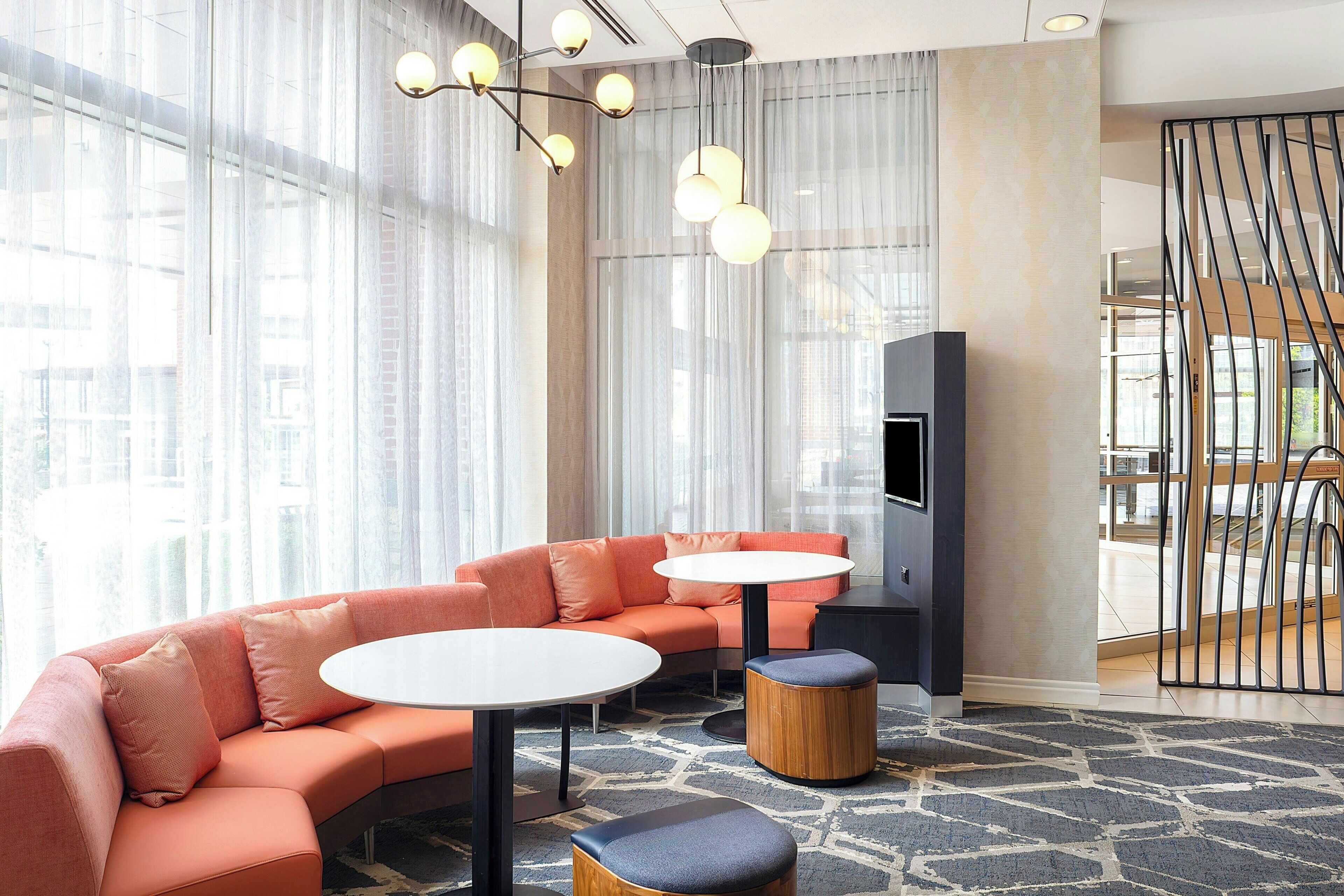 A modern lounge area with a curved sofa, two round tables, and a TV.