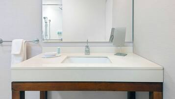 A bathroom with a white sink, a mirror, and a towel rack.