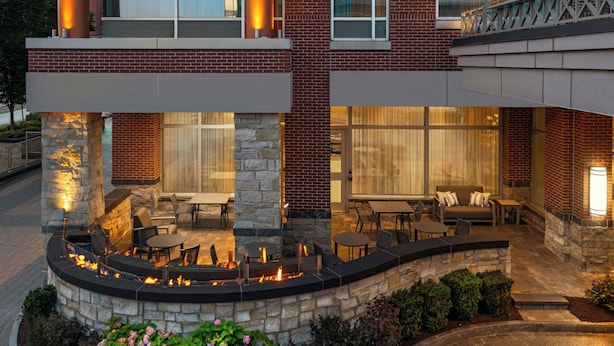 Une terrasse extérieure moderne, avec des murs en pierre, un foyer et du mobilier d’extérieur.