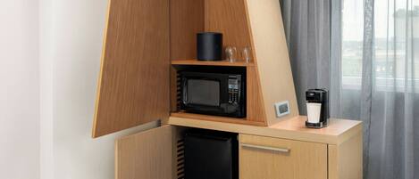 Une petite cuisine équipée d’un four à micro-ondes, d’une machine à café et d’un petit réfrigérateur.