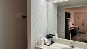 Un baño de hotel con un espejo grande, un lavabo y una zona de ducha.