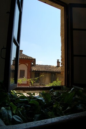 A window with a view of traditional buildings and a garden. - B&B Relais il Casato (Siena)