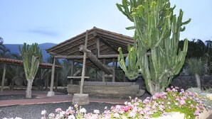 A wooden pavilion with a tiled roof, surrounded by cacti and flowering plants. - Hotel Rural Finca Salamanca (Güímar)