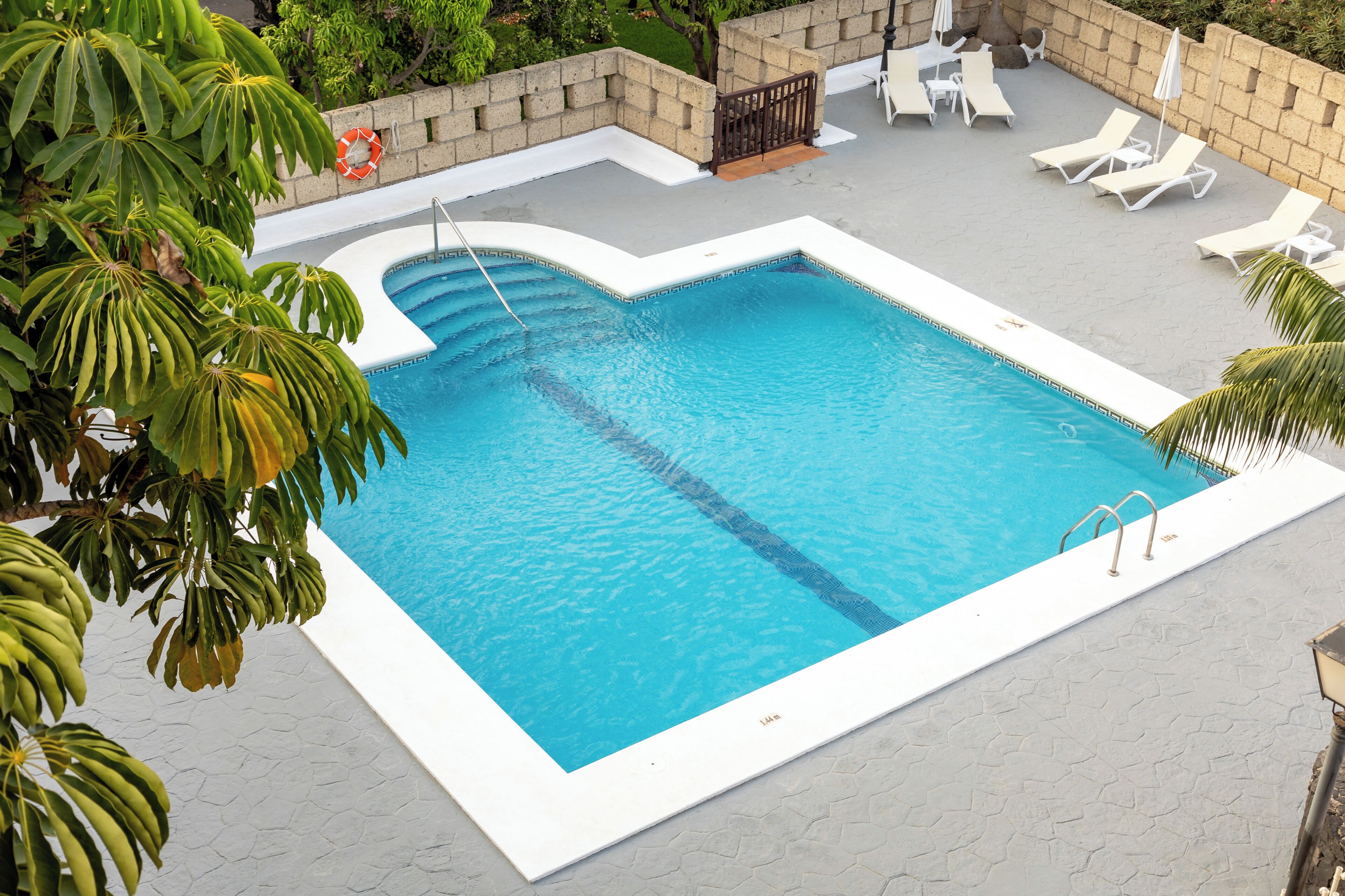 Una piscina rectangular con borde blanco y un flotador anclado a la pared.