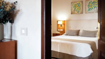 Habitación de hotel con cama, mesita de noche, lámpara y dos obras de arte colgadas en la pared.