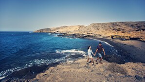 A rocky beach with clear blue water and a mountainous backdrop. - Hotel Rural Finca Salamanca (Güímar)