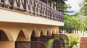A building with a balcony, arched windows, and a tiled walkway.