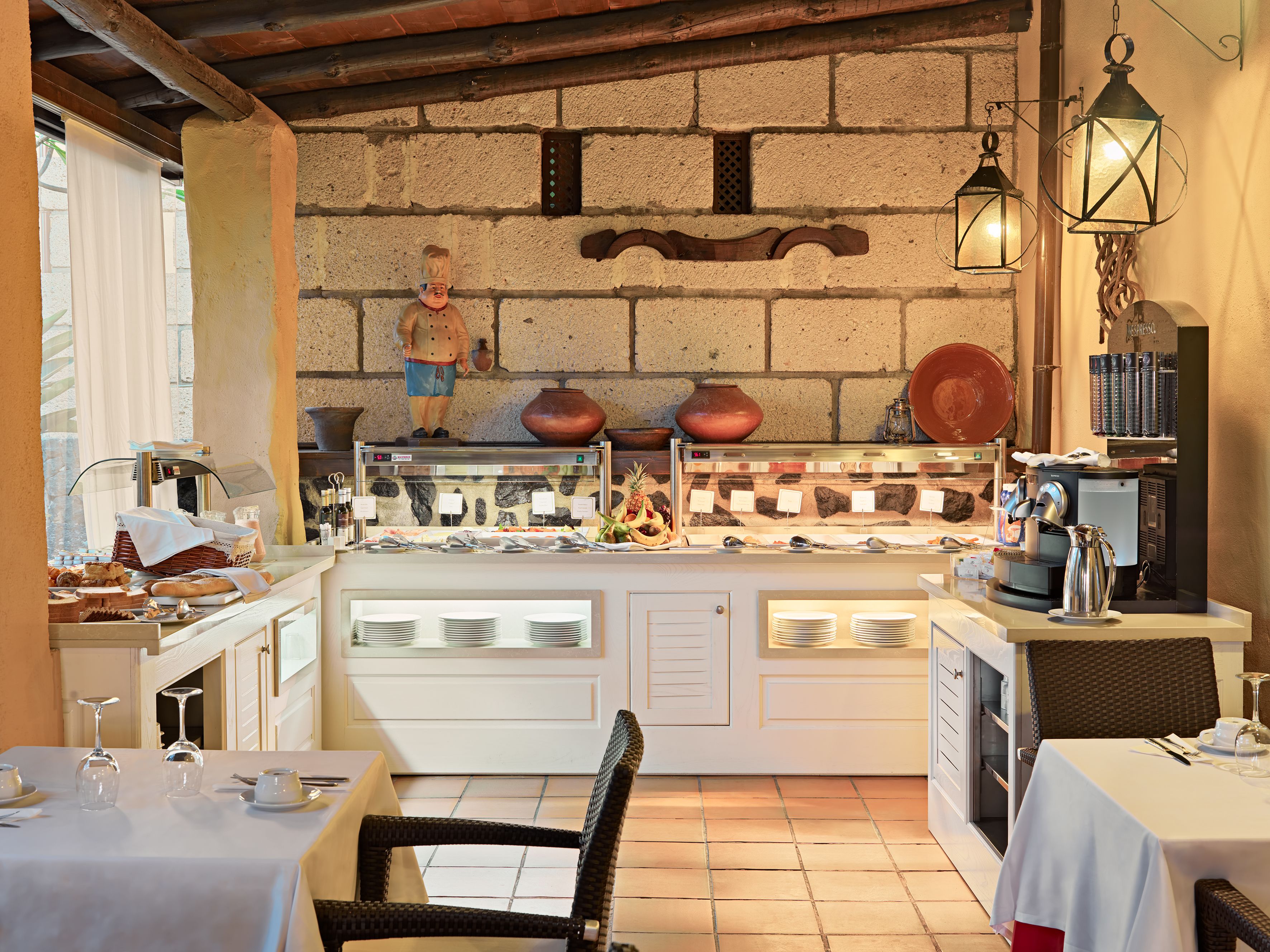 A cozy restaurant with a stone wall, a buffet with various dishes, and a coffee machine.
