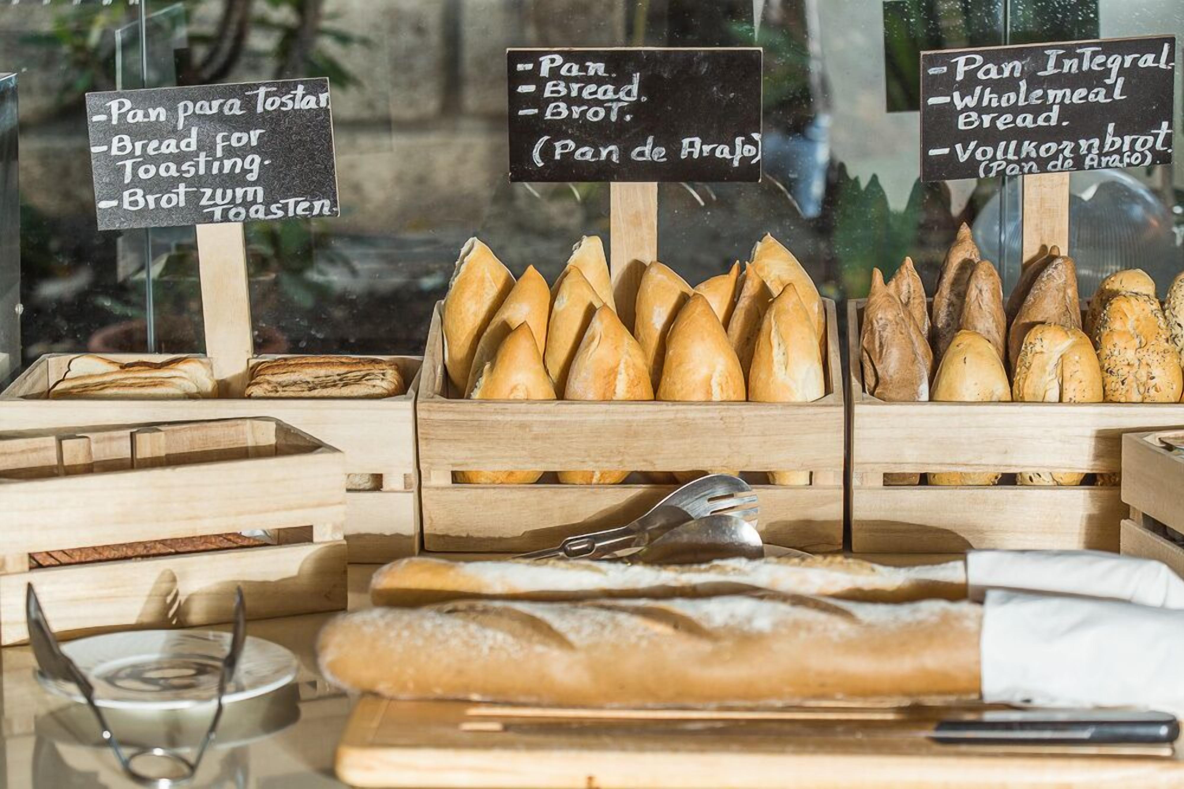 A bakery display with various types of bread, including baguettes and wholemeal bread, arranged in wooden crates.