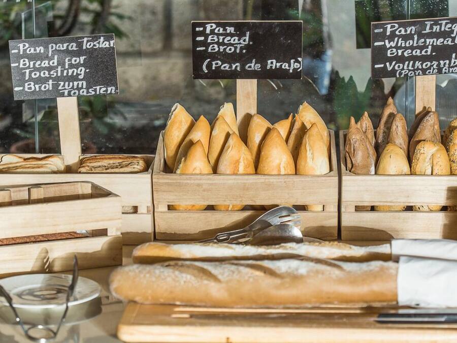 Eine Bäckereiauslage mit verschiedenen Brotsorten, darunter Baguettes und Vollkornbrot, ansprechend in Holzkisten angeordnet.