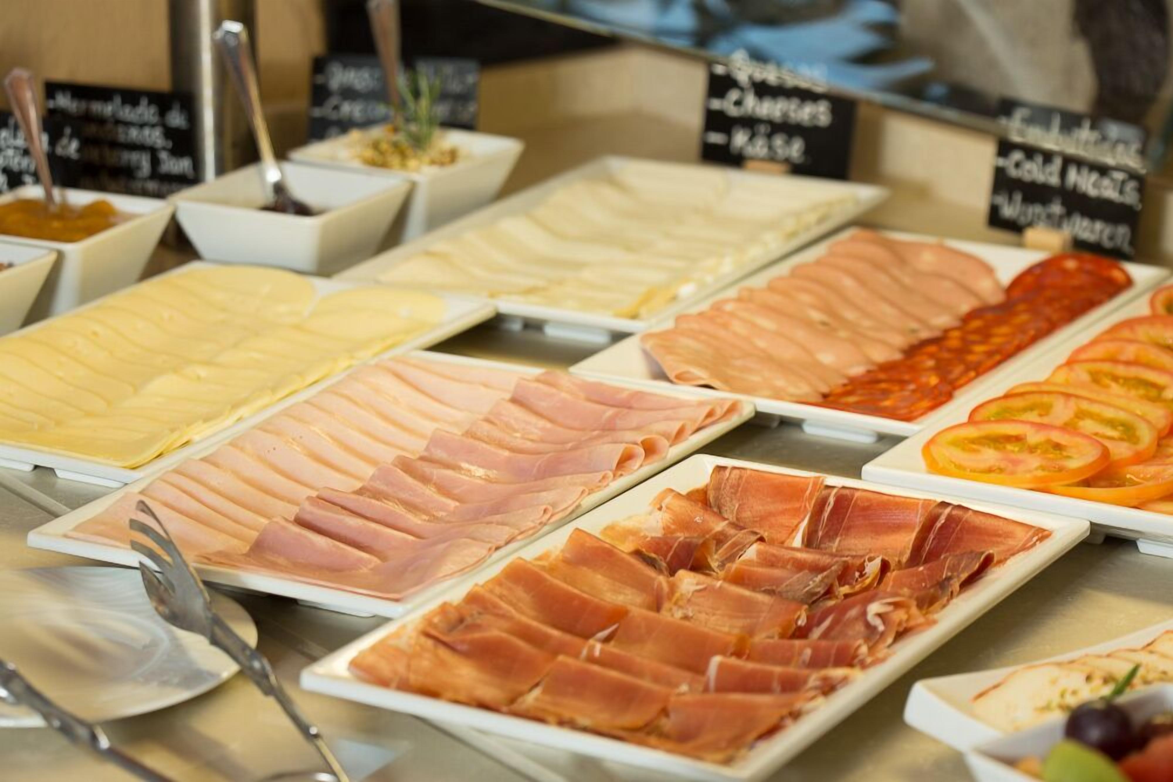 A buffet with various meats and cheeses.
