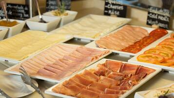 A buffet with various meats and cheeses.