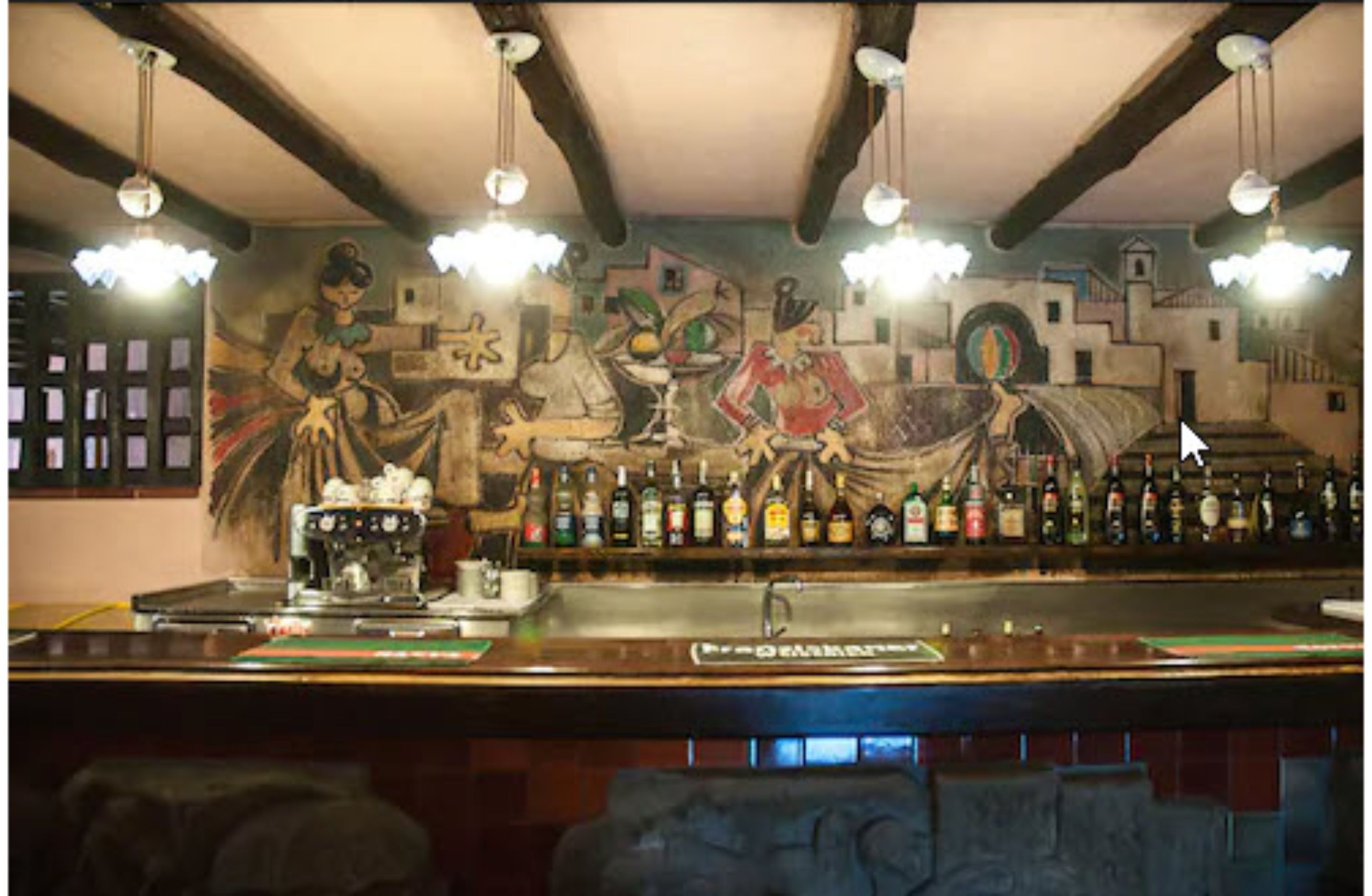 A bar with a mural on the wall, a bar counter, and various bottles of alcohol.