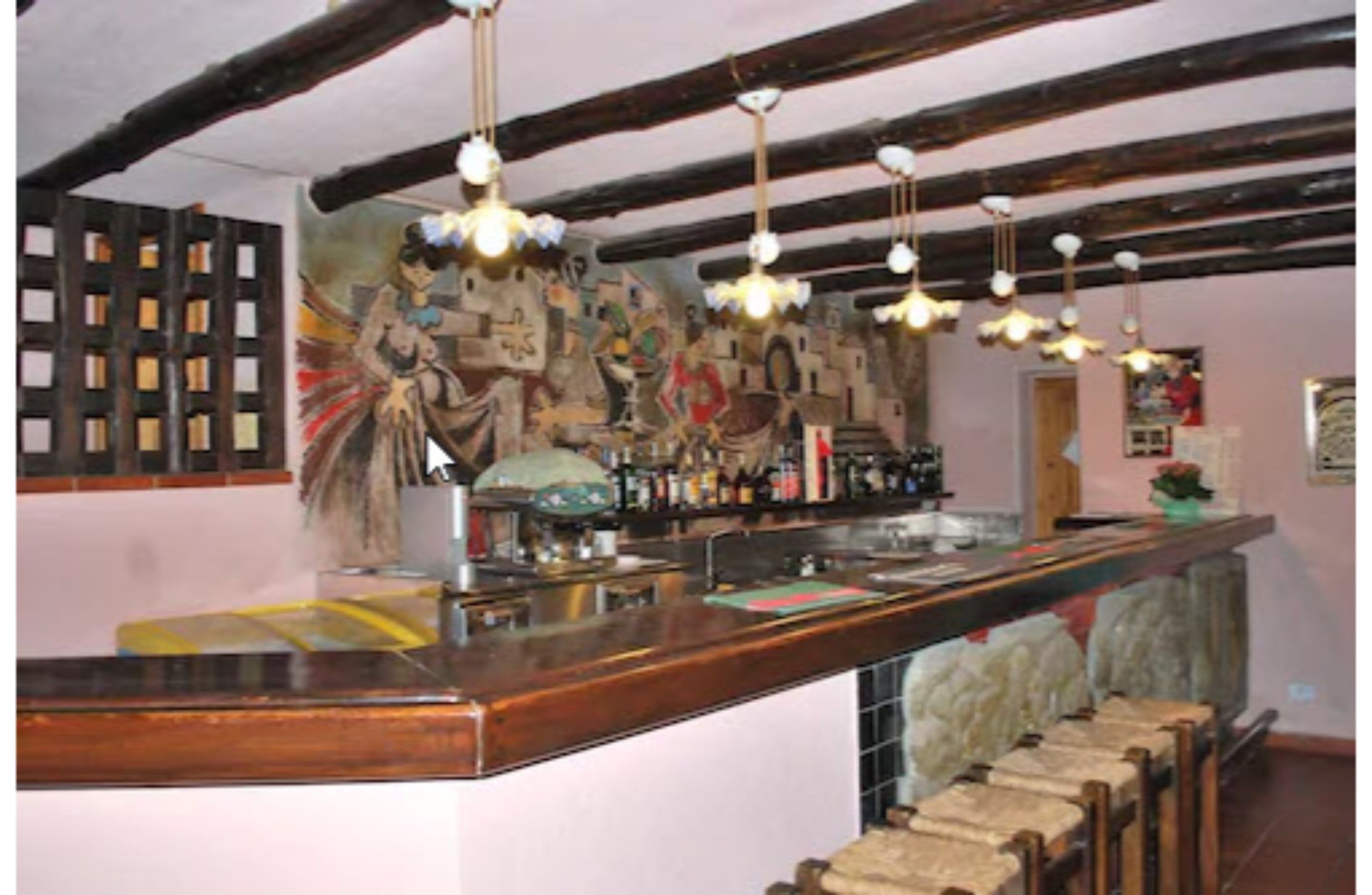 Een bar met houten balken, hangende lampen en een muurschildering.