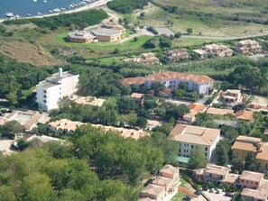 An aerial view of a coastal residential area with a mix of single and multi-story buildings, some with flat roofs and others with sloped roofs. - Hotel Scintilla (San Teodoro)
