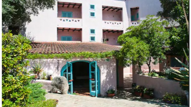 A building with a white facade, multiple balconies, and a tiled roof. - Hotel Scintilla (San Teodoro)