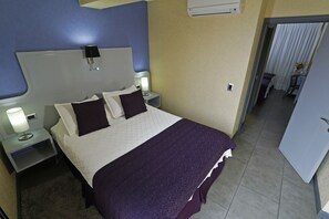 Habitación de hotel con una cama grande, dos mesitas de noche con lámparas, cabecera y un equipo de aire acondicionado en la pared.
