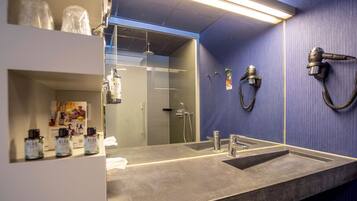 Un baño moderno con un espejo grande, un lavabo y un secador de pelo montado en la pared.