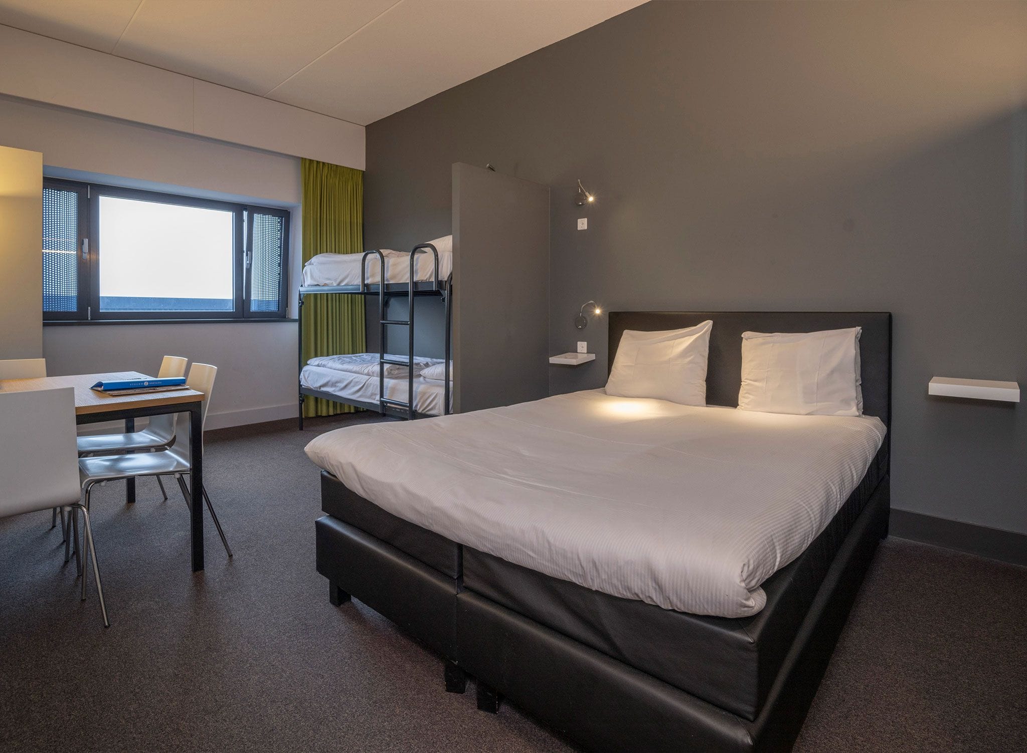 Ein modernes Hotelzimmer mit einem großen Bett, einem Schreibtisch und einem Stockbett.