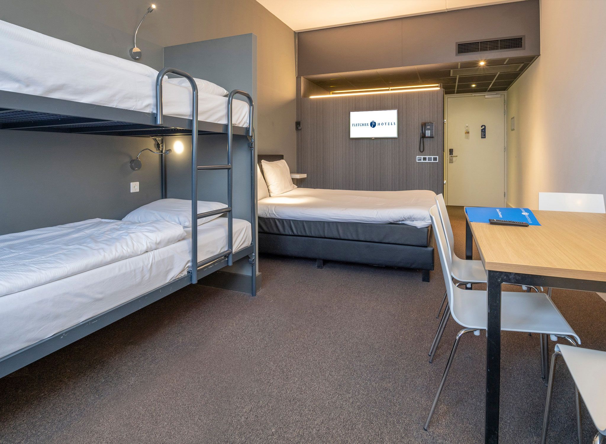 Une chambre d’hôtel avec des lits superposés, un bureau et une chaise.
