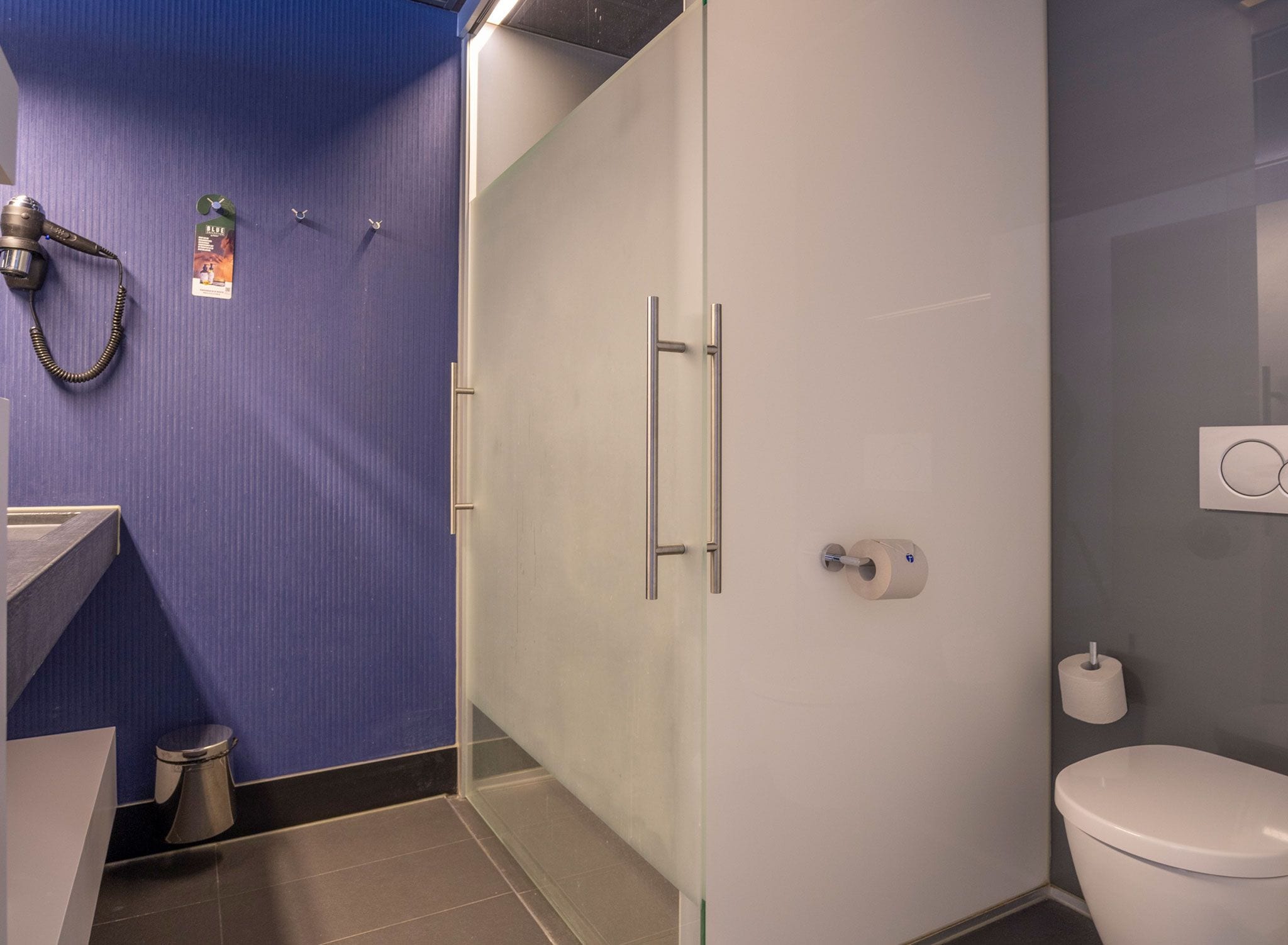 Un baño moderno con cabina de ducha de vidrio, inodoro y lavamanos.