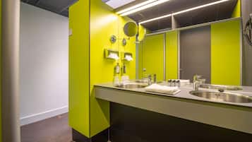 Un baño moderno con dos lavamanos, un espejo y paredes de color verde brillante.