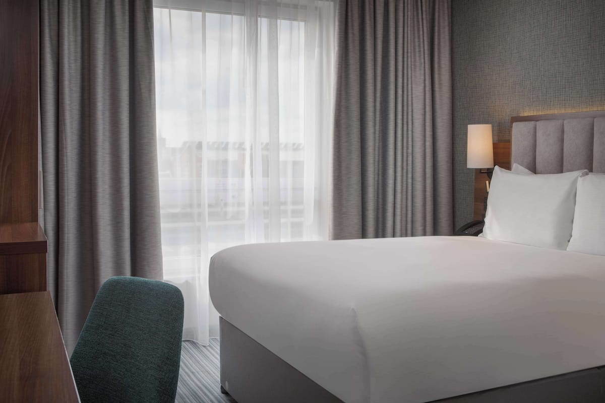 A hotel room with a large bed, a desk, and a chair.