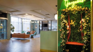 Un vestíbulo de hotel moderno con mostrador de recepción, zona de estar y ventanas amplias.