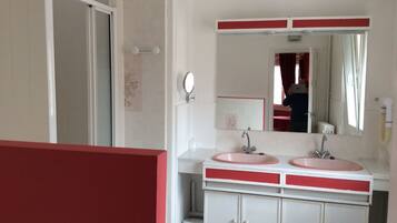 Une salle de bain avec deux lavabos, un miroir et des toilettes.