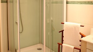 A glass-enclosed shower with a white towel rack and a white towel. - Hotel du Cygne (Beauvais)